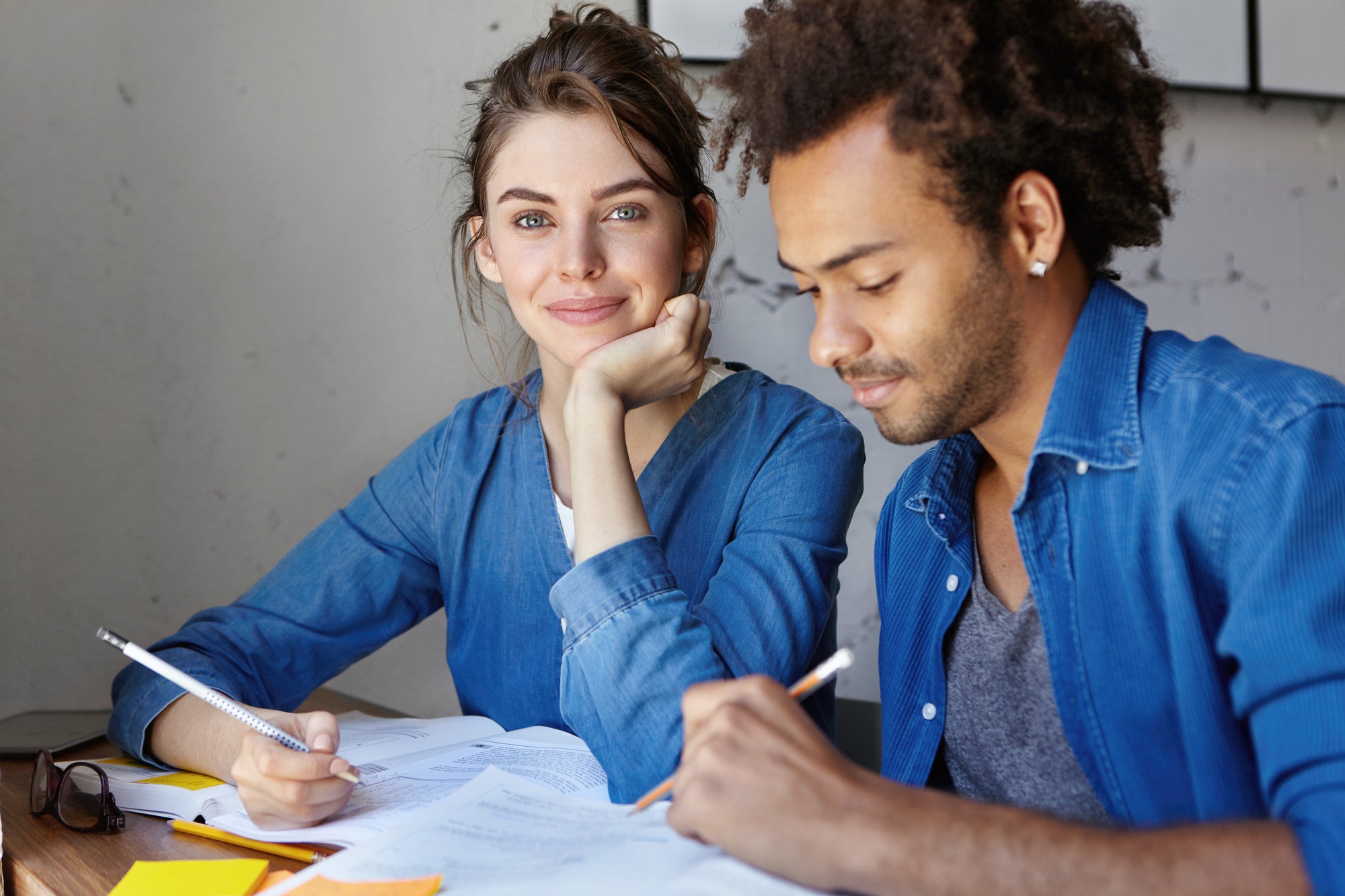 Beautiful young female tutor teaching Afro American student private lesson, checking homework, encou Beautiful young female tutor teaching Afro American student private lesson, checking homework, encou